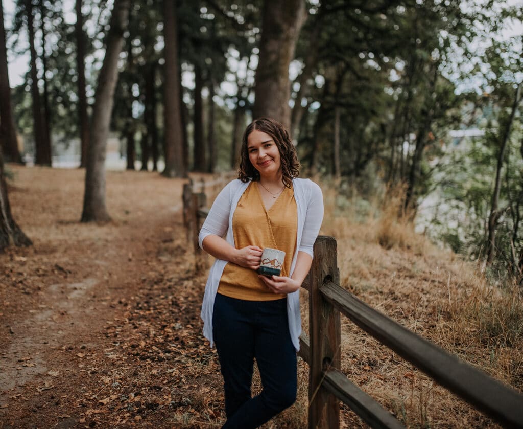 Stephanie standing holding mug in forest